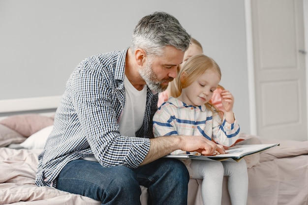 La parentalité. Jolie fille assise avec grand-père dans la chambre. Lire ensemble un livre.