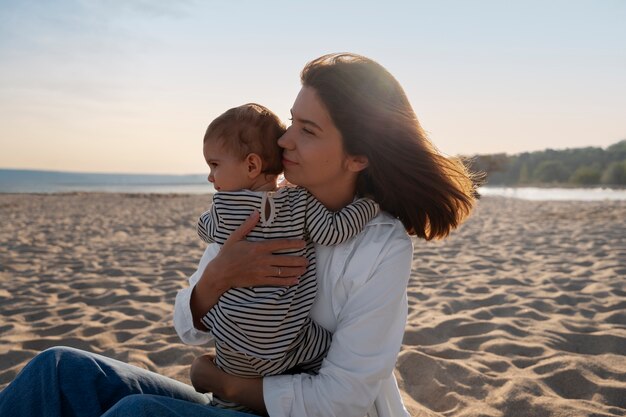 Parents avec un bébé sur la plage au coucher du soleil