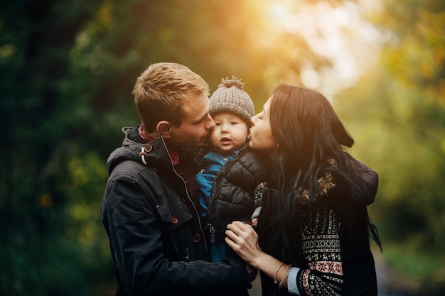 Photo gratuite les parents embrassent l'enfant dans le parc