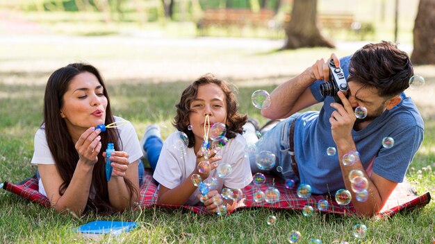 Parents et enfants faisant des bulles ensemble dans le parc