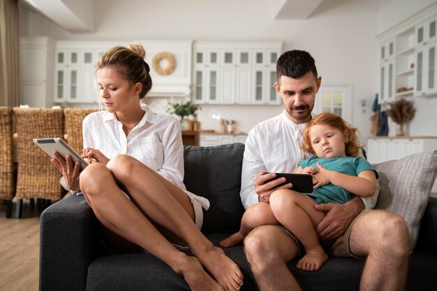 Parents et enfants de plan moyen avec des appareils