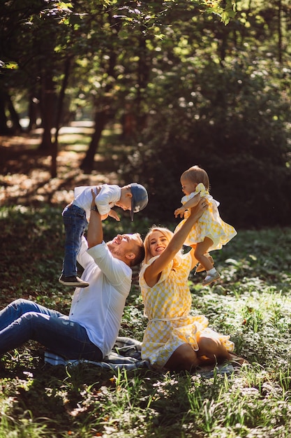 Photo gratuite les parents étonnants s'amusent avec leurs deux reposant sur une pelouse verte dans le parc