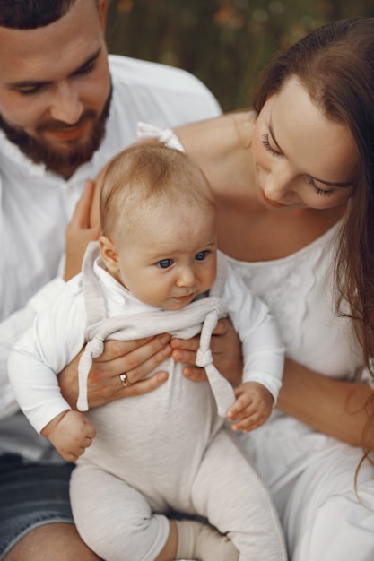 Parents avec fille. Famille dans un champ. Fille nouveau-née. Femme en robe blanche.