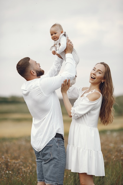 Parents avec fille. Famille dans un champ. Fille nouveau-née. Femme en robe blanche.