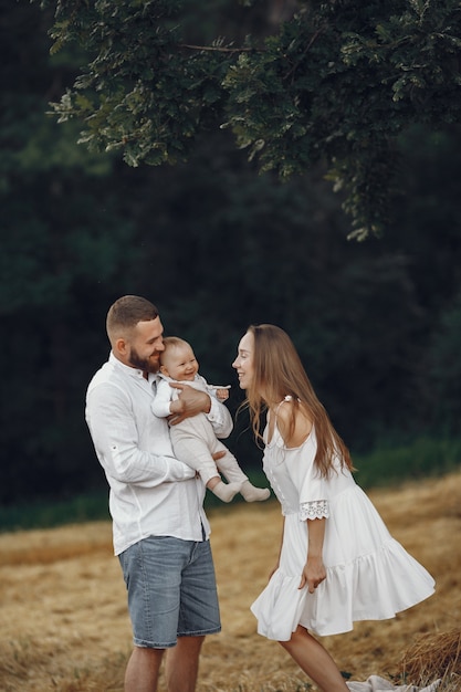 Parents avec fille. Famille dans un champ. Fille nouveau-née. Femme en robe blanche.