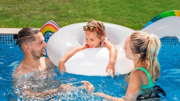 Photo gratuit des parents heureux et leur fille dans un anneau en caoutchouc nagent dans la piscine
