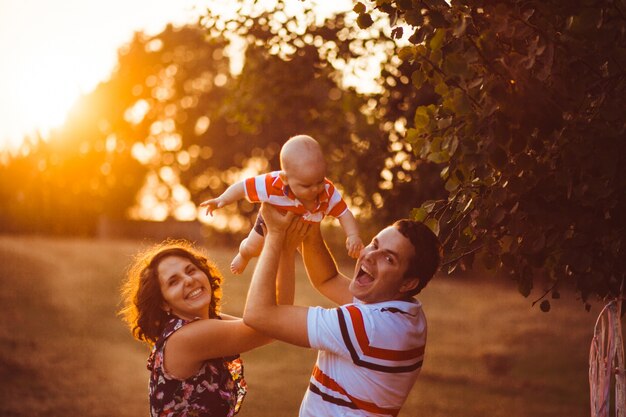 Les parents joyeux tiennent leur petit fils debout à l&#39;extérieur