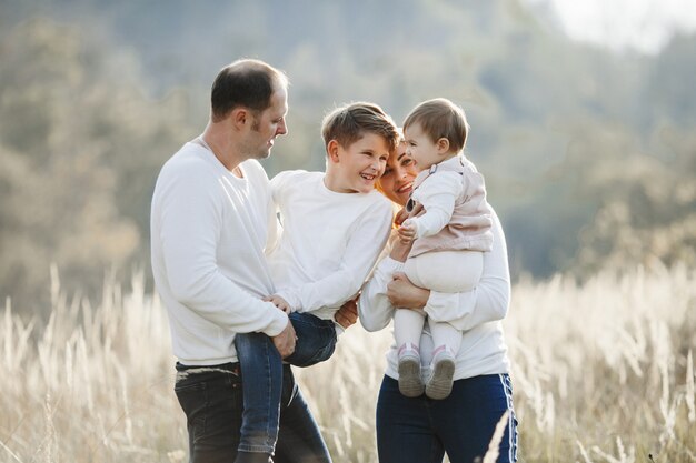 Les parents tiennent la main de leur fils et de leur fille et s'amusent sur le champ de blé