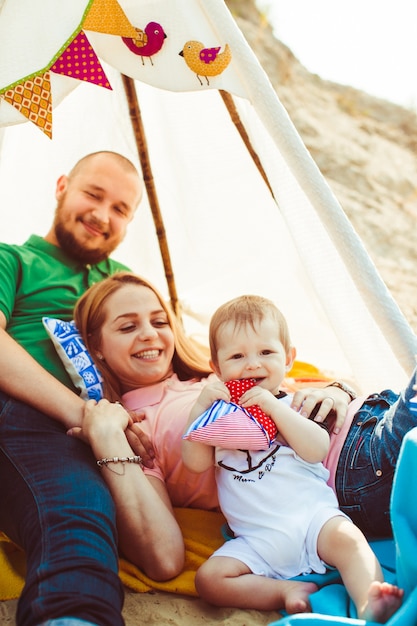Photo gratuite les parents tiennent un petit fils sur leurs bras sous la tente