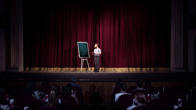 Parler aux étudiants. Orateur féminin donnant une présentation dans le hall à l'atelier. Centre d'affaires. Vue arrière des participants en audience. Événement de conférence, formation.