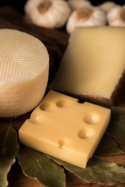 Photo gratuite parmesan et emmental avec des feuilles de laurier sur une table en bois