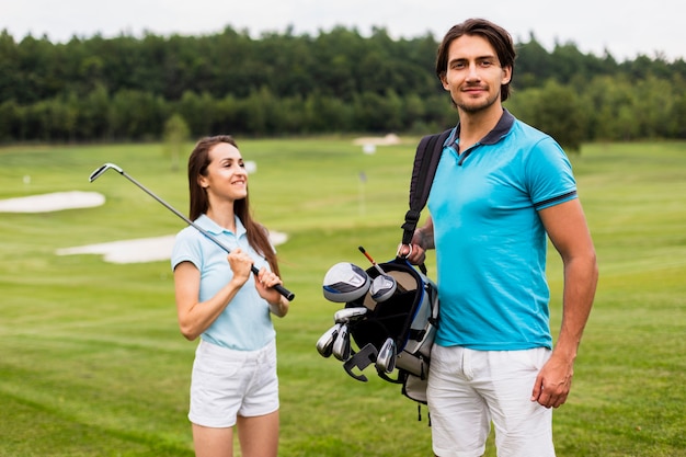 Photo gratuite partenaires de golf portant un sac de golf