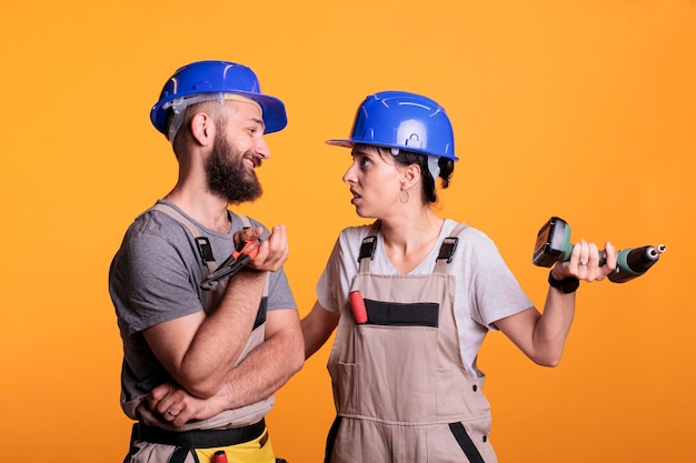 Photo gratuite partenaires d'ingénierie discutant de différentes idées de projet de construction, travaillant en équipe sur la rénovation. équipe de rénovateurs travaillant ensemble à l'aide d'un pistolet de forage et d'une paire de pinces en studio.