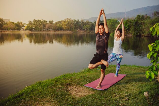 Partenaires de yoga équilibrés à côté du lac