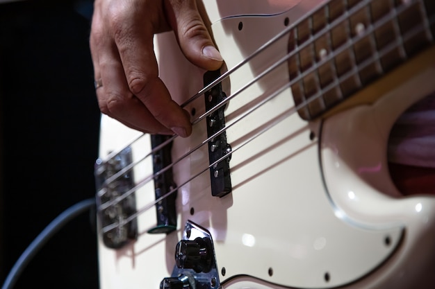 Une partie de la guitare basse se bouchent tout en jouant sur un fond noir.