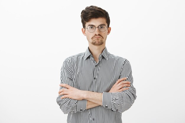 Pas mal, vraiment. Portrait de respectueux employé européen strict satisfait, tenant les mains croisées sur la poitrine et faisant face à l'esturgeon heureux tout en voyant quelque chose de satisfaisant sur un mur gris