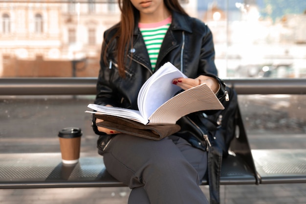 Photo gratuite passager assis sur un banc de gare et lit