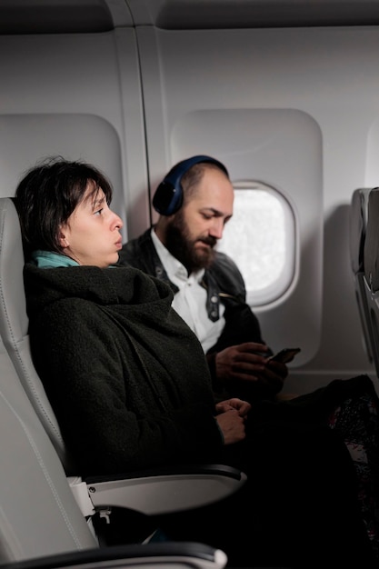 Passagère se sentant tendue et effrayée par le décollage de l'avion, ayant peur de voler à l'étranger. Voyager avec des compagnies aériennes internationales pour partir à l'aventure en vacances, vol commercial.