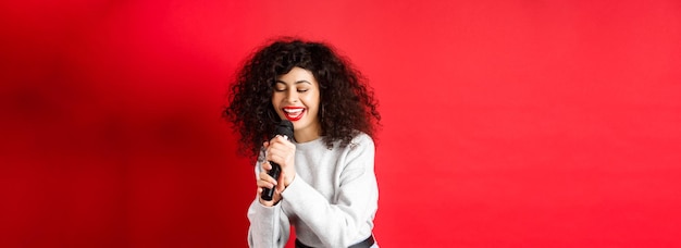 Photo gratuite passe-temps et concept de loisirs belle femme chantant dans le microphone et souriant s'amusant au karaoké