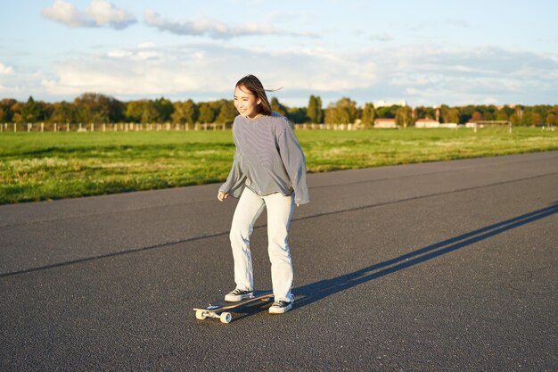 Passe-temps et style de vie jeune femme équitation skateboard skater fille profitant d'une croisière sur longboard sur sunn