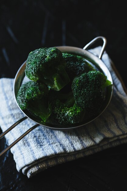 Passoire de fleurons de brocoli sur fond noir.