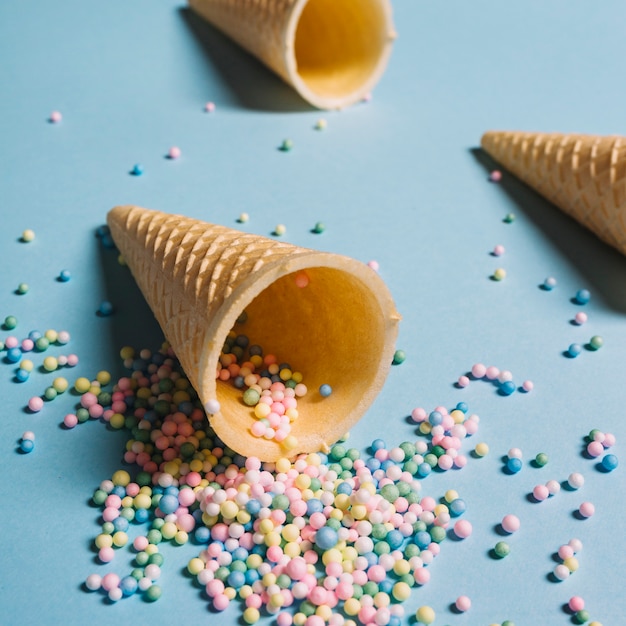 Photo gratuite pastel couleur pépites déversant de cône de gaufre sur fond bleu