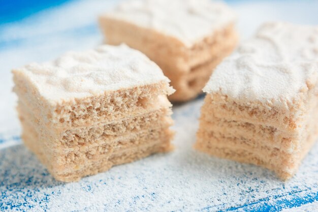 Pastila morceaux sur le fond en bois bleu recouvert de sucre en poudre, vue de côté