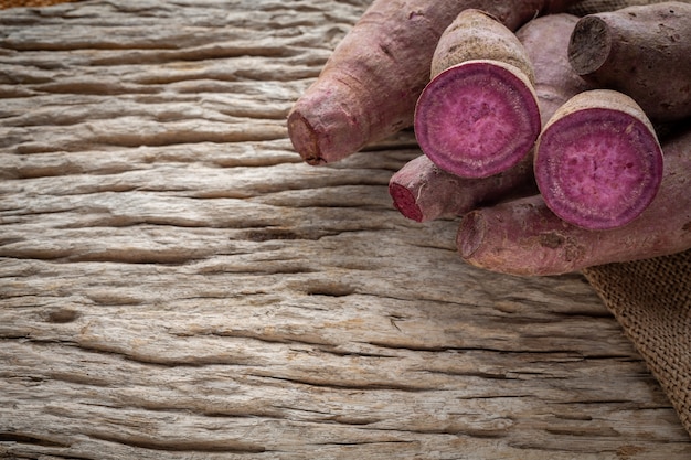 Photo gratuite patate douce violette posée sur un plancher de bois brun.