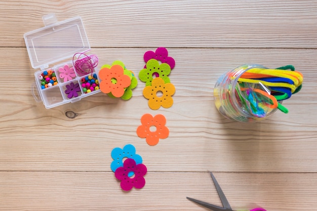 Patch de fleurs colorées; tiges de chenille; et boîte de perles sur fond en bois