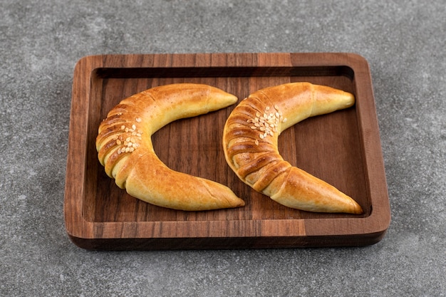 Pâté en bois de deux délicieux biscuits à la vanille en forme de croissant sur table en marbre.