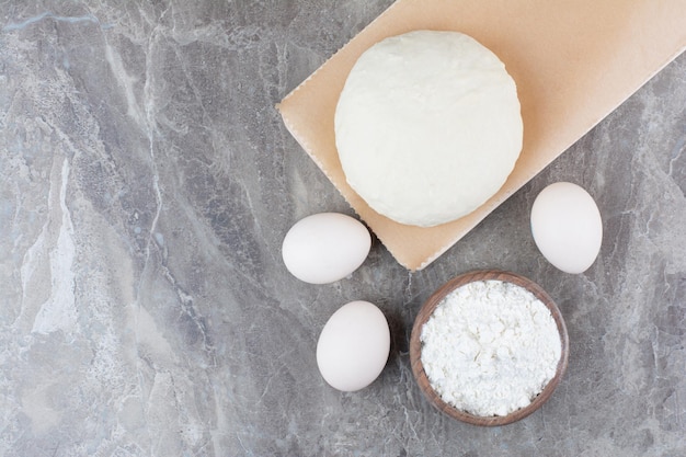Pâte avec de la farine et des œufs de poule sur fond de marbre. photo de haute qualité