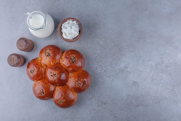 Photo gratuite pâte fraîche en forme de fleur avec de la crème et pot de lait sur fond de pierre.