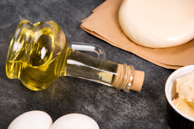 Photo gratuite pâte, huile, fromage et œufs sur une surface en bois grise