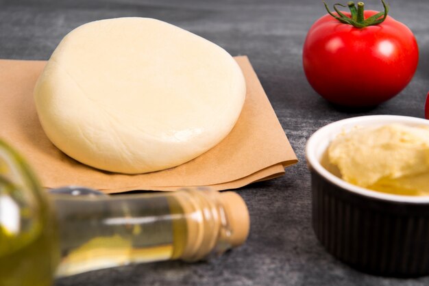 Pâte, huile, fromage et œufs sur une table en bois gris