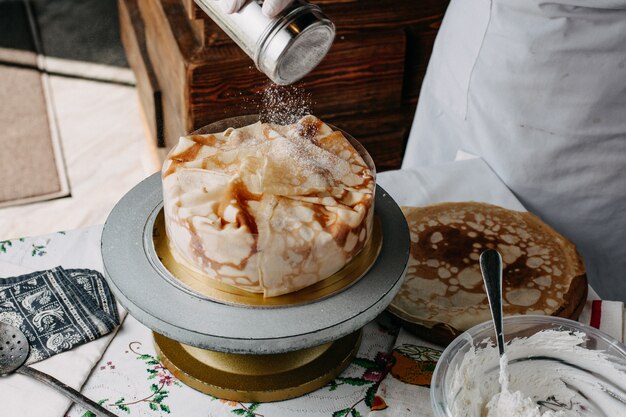 Pâte à l'intérieur de la poêle ronde avec cuisinier étalant des tranches de cuisson des repas sur elle à l'intérieur de la cuisine