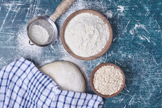 Photo gratuite pâte à pain avec des ingrédients sur table bleue.