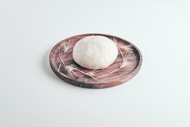 Pâte à pain ronde à la main dans un plateau en bois au milieu.