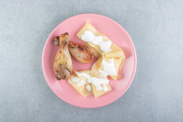 Pâtes au yaourt et cuisse de poulet sur plaque rose.