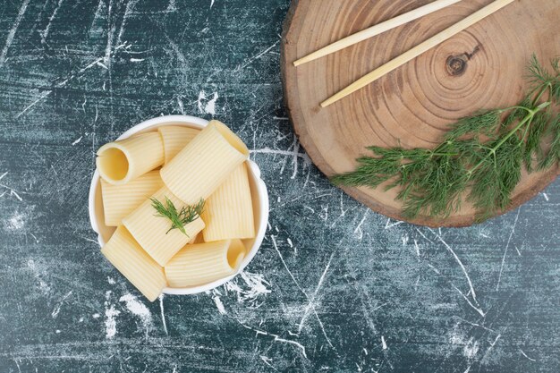 Pâtes bouillies dans un bol blanc avec des baguettes et de la coriandre. Photo de haute qualité