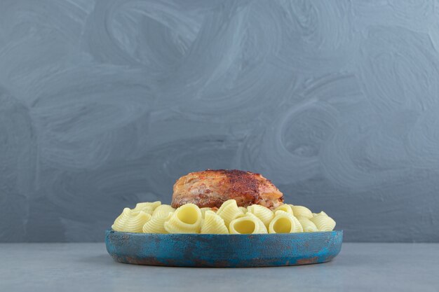 Pâtes Conchiglie et poulet grillé sur plaque bleue.