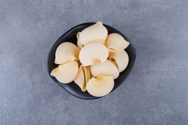 Pâtes de coquillage crues dans un bol noir.