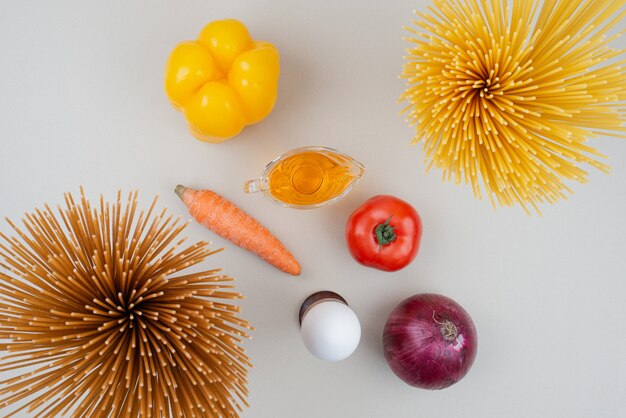 Pâtes crues aux légumes sur blanc.