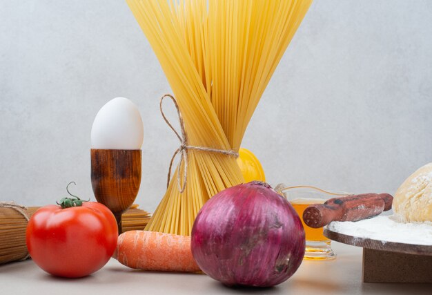 Pâtes crues aux légumes sur blanc.