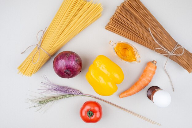 Pâtes crues aux légumes sur une surface blanche