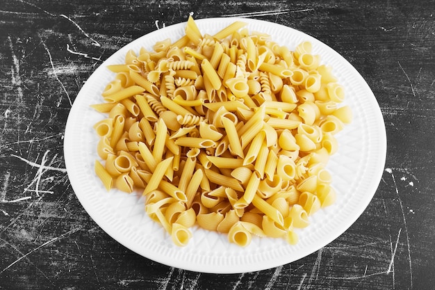 Pâtes crues dans une assiette blanche.