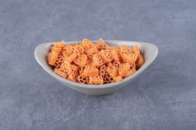 Pâtes crues en forme de coeur dans un bol en céramique.