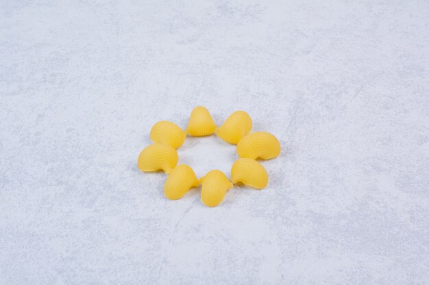 Pâtes crues en forme de coquillage sur une surface blanche