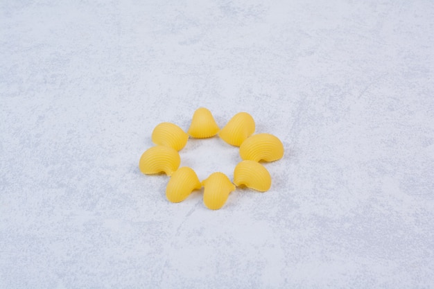 Pâtes crues en forme de coquillage sur une surface blanche