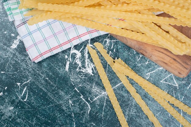 Pâtes crues jaunes avec nappe sur espace bleu.