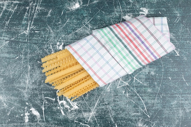 Photo gratuite pâtes crues jaunes avec nappe sur fond bleu. photo de haute qualité